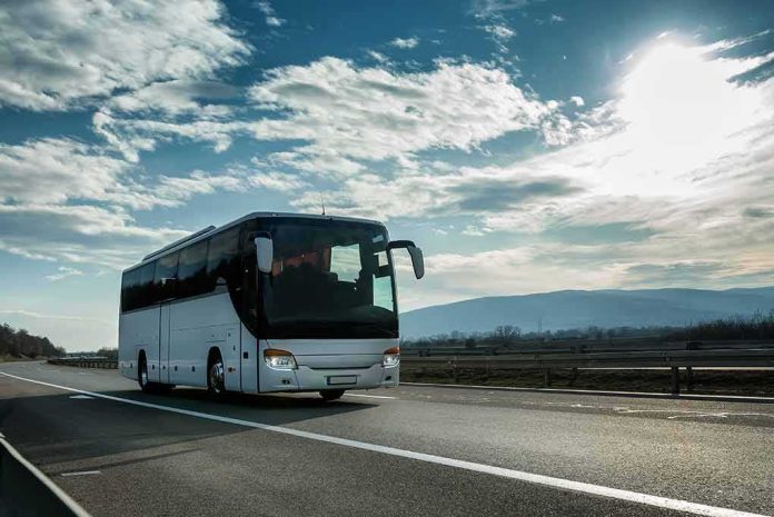 shutterstock_1654594828 White coach bus driving on a highway under a bright sky