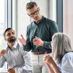 Team meeting with three colleagues discussing around a table