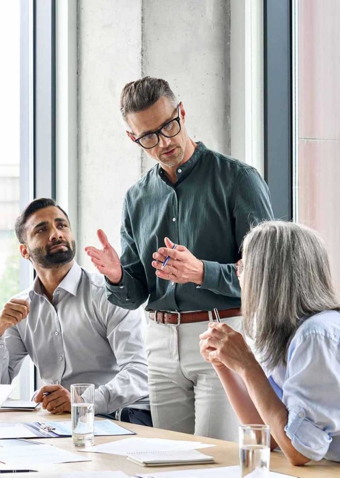 shutterstock_2024994161 Team meeting with three colleagues discussing around a table