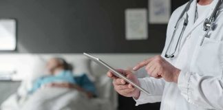 Doctor using tablet beside hospital patient