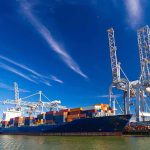 Container ship docked at port with cranes loading cargo