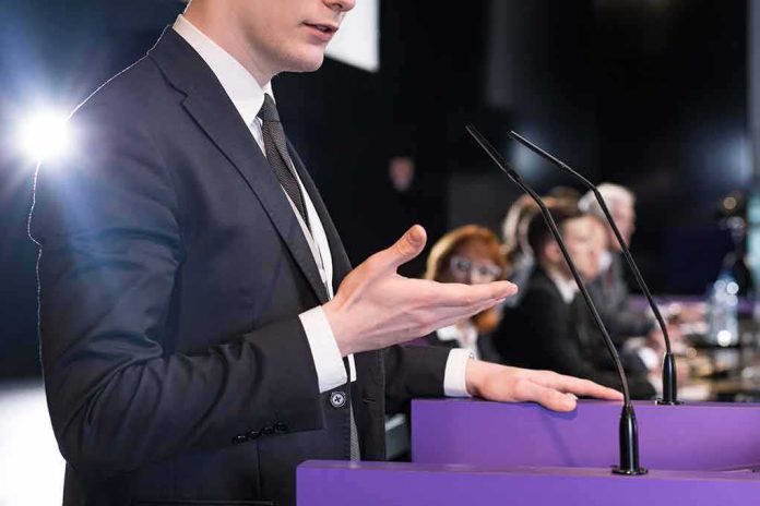shutterstock_451629085 Speaker in suit at podium gesturing during conference