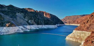 Lake Powell COLLAPSES: River Faces New Strain Reservoir between rugged desert cliffs with stark white shoreline