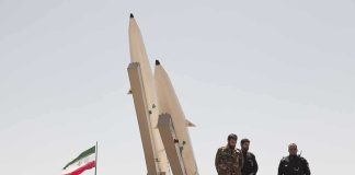 Soldiers stand beside large missiles at an outdoor display