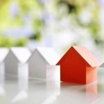 Red paper house among white paper houses