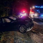 Crashed car on a dark roadside with emergency vehicles