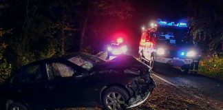 Elite Runner Dies Hours Before Marathon Crashed car on a dark roadside with emergency vehicles