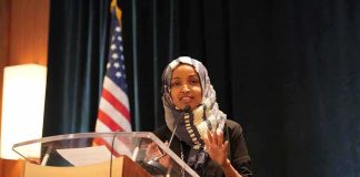 FBI Probe Into Omar Raises DNA Questions Woman in hijab speaking at a podium