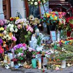Memorial with flowers, candles, and tributes on a sidewalk