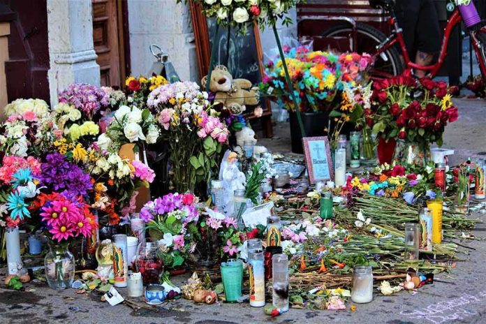shutterstock_1474073639 Memorial with flowers, candles, and tributes on a sidewalk