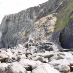 rocky coastal cliff with large boulders at its base