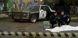 Witnesses Question ICE Use of Force Crime scene with police car and two investigators by a covered body