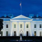 White House illuminated at dusk with flagpole and columns