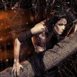 Fantasy-styled person crouching on a fallen tree in a dark forest
