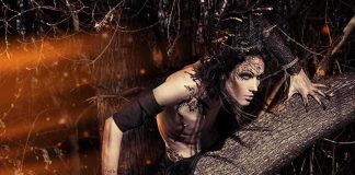 Fantasy-styled person crouching on a fallen tree in a dark forest