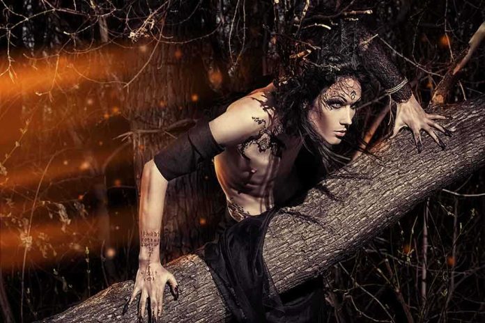 shutterstock_193640750 Fantasy-styled person crouching on a fallen tree in a dark forest