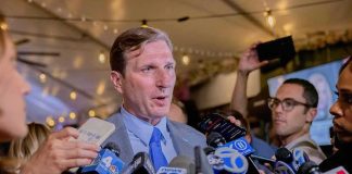 Hollywood Star Opens Up About Losing Faith Man in suit speaks to reporters surrounded by microphones