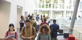 Virginia State Faces Lawsuit Over Christian Clubs Students walking through a bright campus lobby using mobile devices