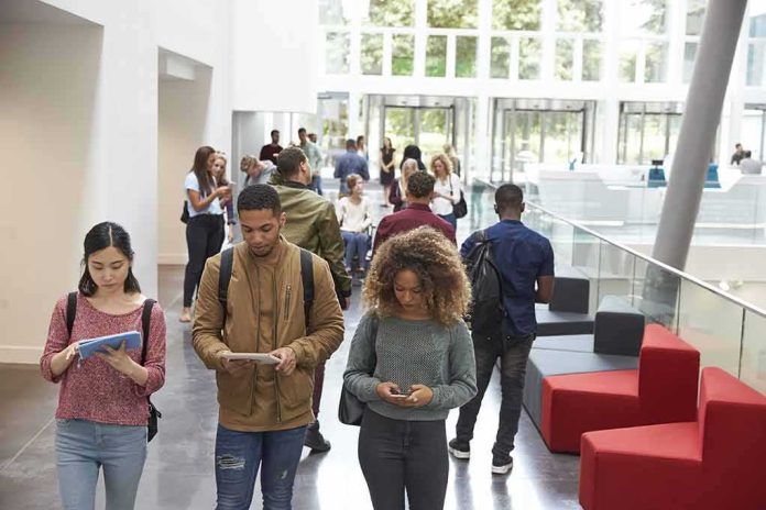 Students walking through a bright campus lobby using mobile devices