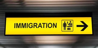 UK Reopens Refugee Resettlement Routes Immigration sign with arrow in airport
