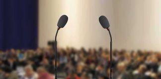 Podium with two microphones facing a blurred audience