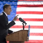 Speaker at podium with microphones in front of US flag